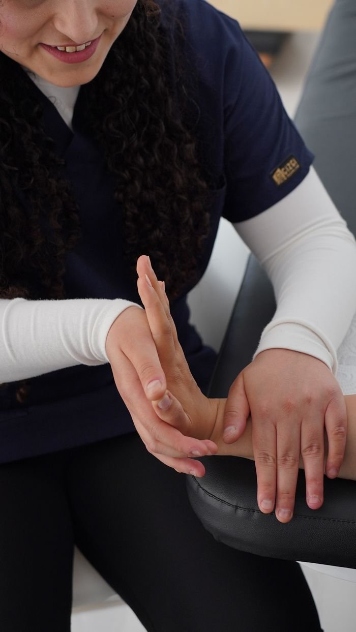 An adult receiving professional hand therapy from a physiotherapist in a clinic setting.