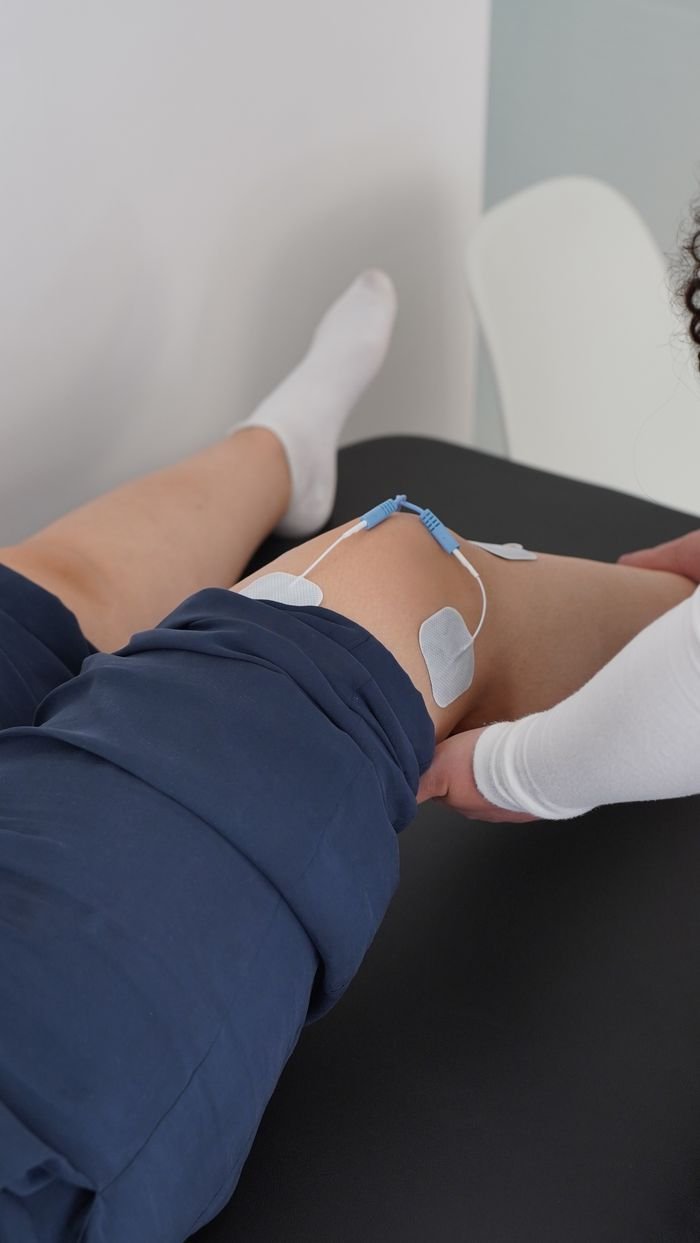 Electrotherapy applied during a knee physiotherapy session for muscle recovery.